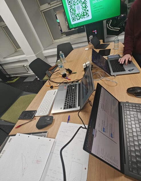 Hackathon table covered in laptops at PlymHack 2026